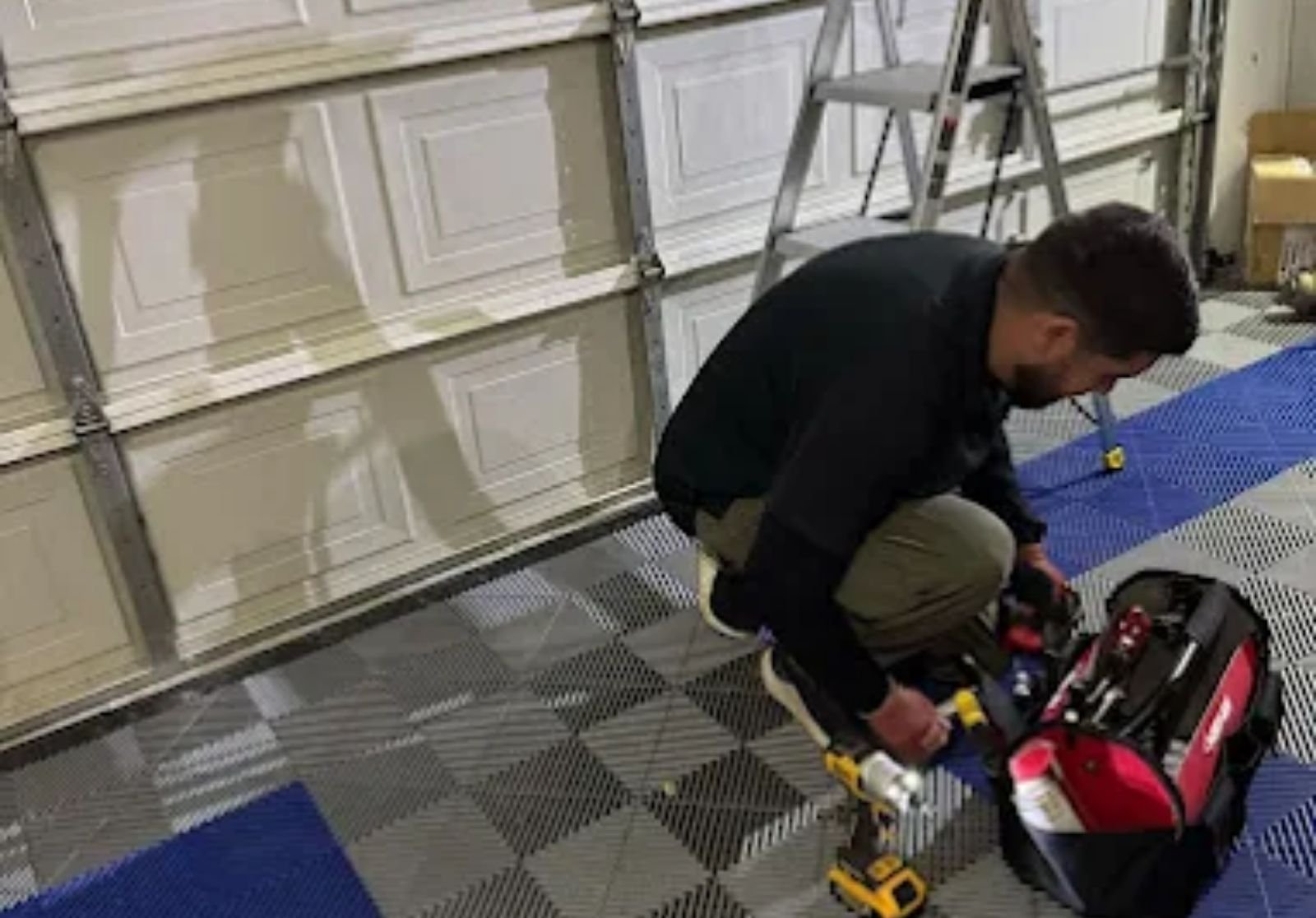 Technician servicing garage door hardware with power tools
