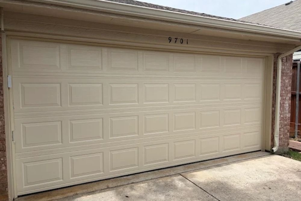 Beige raised-panel double garage door after repair